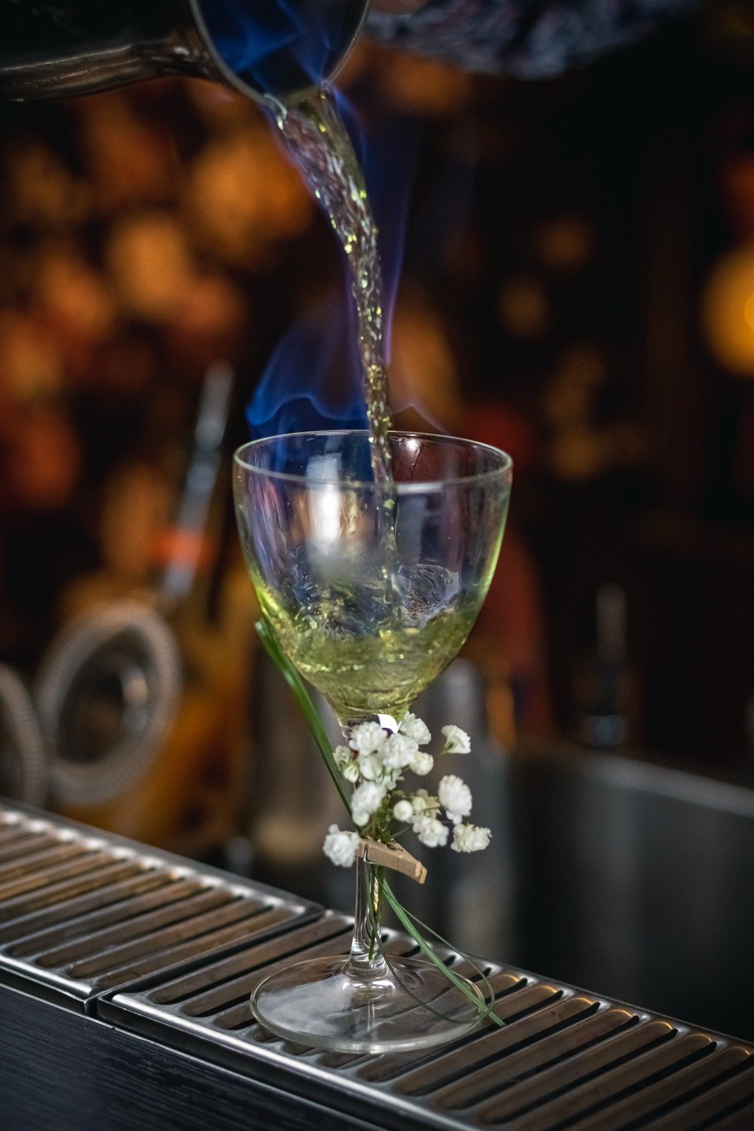 Une création verte dans un verre à pied, enveloppée d’une volute de fumée