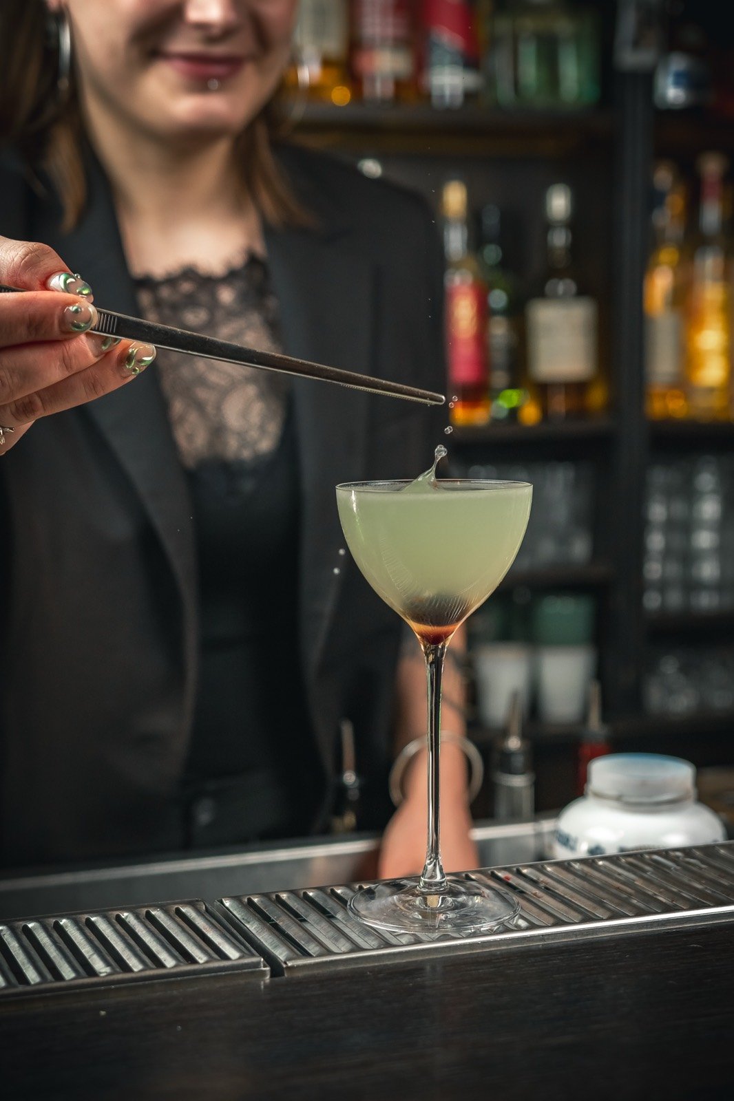 Au comptoir, une bartender apporte la dernière touche à une création